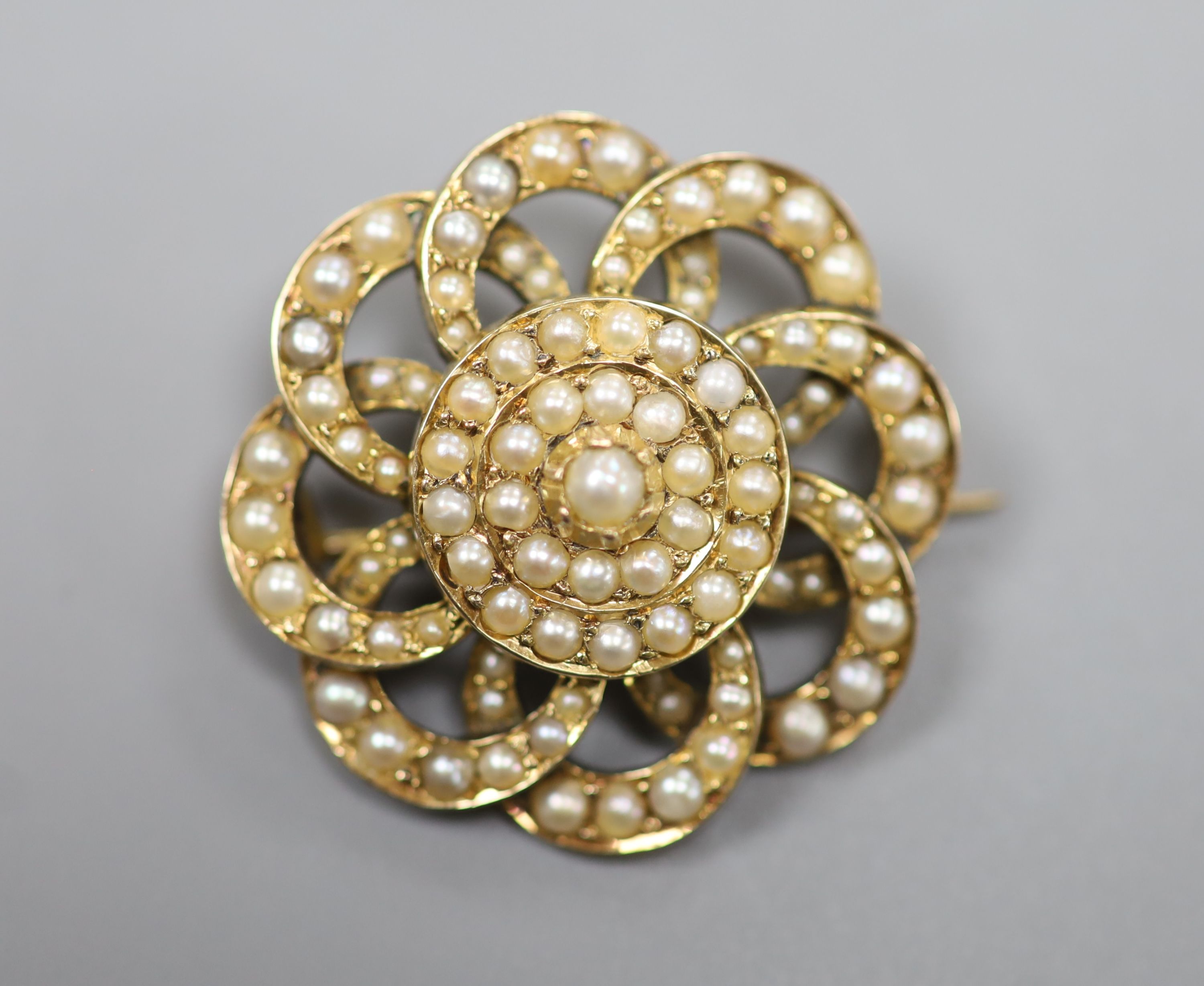 An early 20th century yellow metal and seed pearl set circular cluster brooch, 27mm